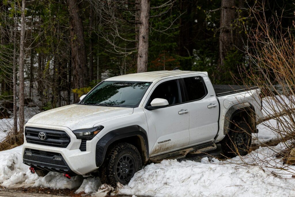 White pickup truck driving through snow and trees